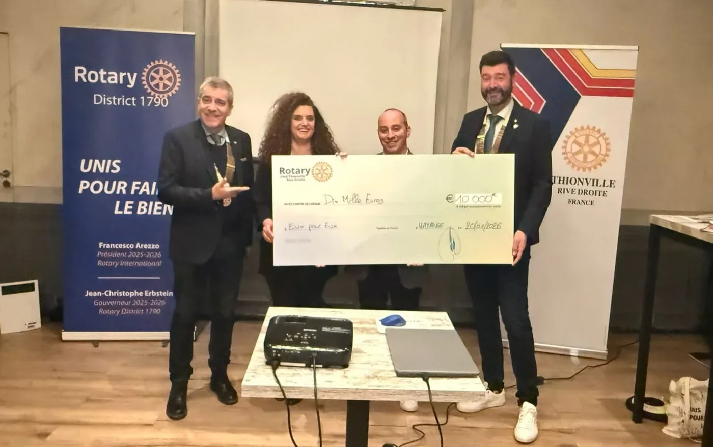 Remise du chèque de 10 000 euros à l’association Eux pour Eux : quatre personnes tiennent un grand chèque du Rotary devant les kakémonos du district 1790 et du club de Thionville Rive Droite